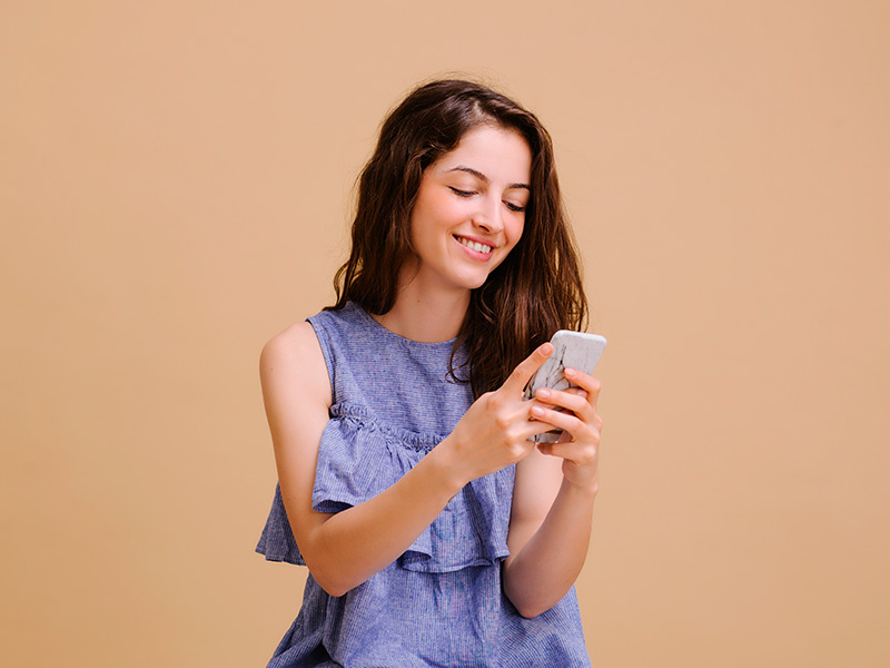 Mulher pesquisando no celular sobre a ptose mamária