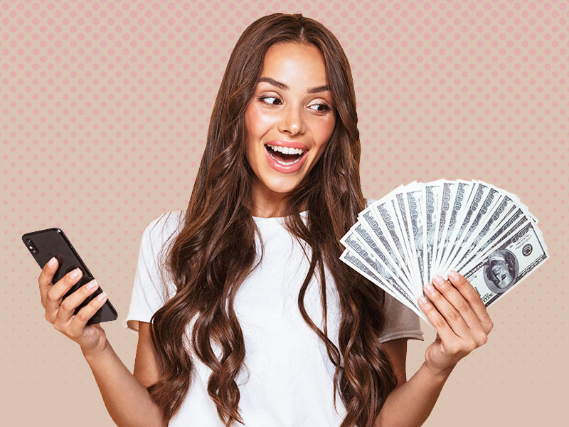 Mulher feliz com celular numa mão e notas de dinheiro na outra vendo que possui o valor para colocar silicone