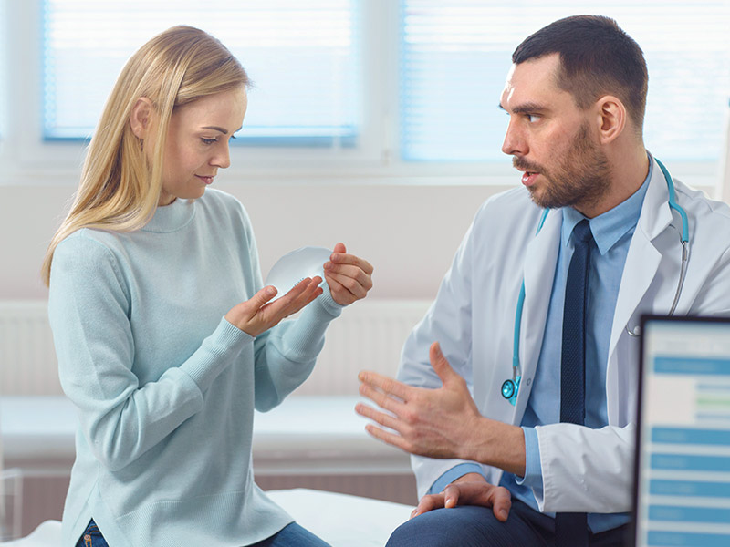 mulher conversando com médico analisando o implante de mama