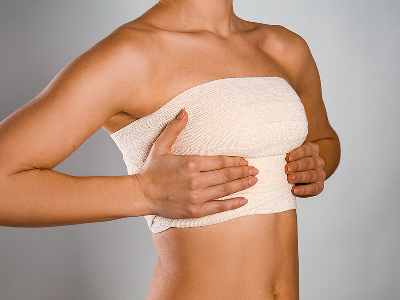 Mulher com a faixa de compressão pós-cirúrgica para evitar a fibrose na mama
