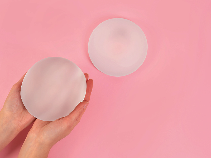 Mão segurando uma prótese de silicone da Lifesil, e outra apoiada mais para frente.