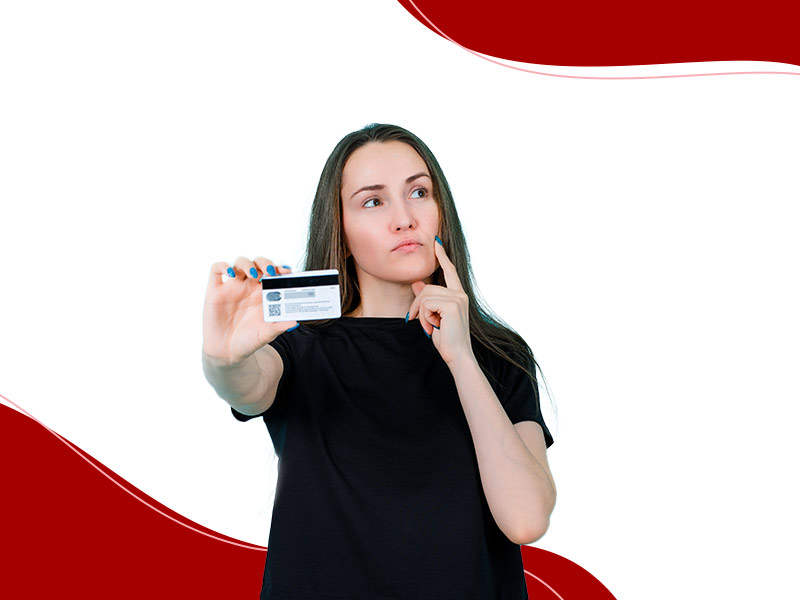 Mulher com a mão no queixo, segurando um cartão de crédito, pensando nas formas de pagamento da abdominoplastia