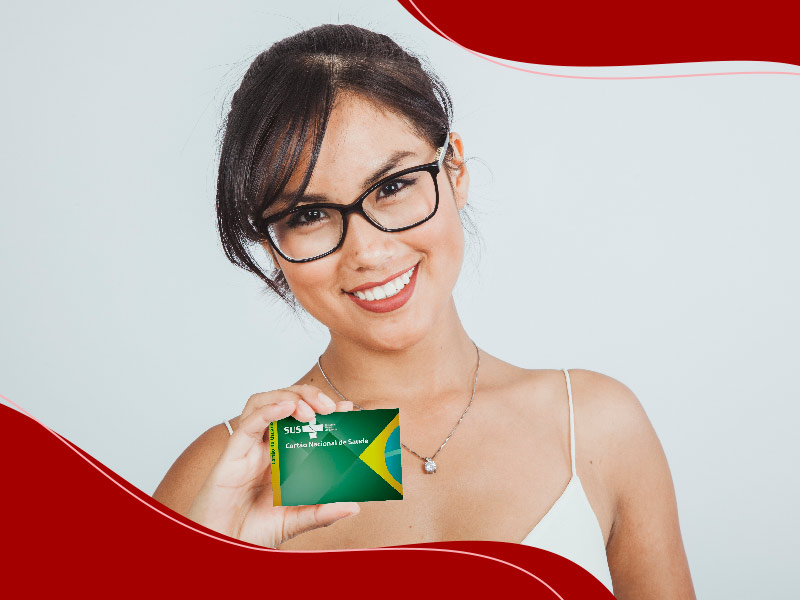 Mulher de óculos sorrindo, segurando um cartão do sus