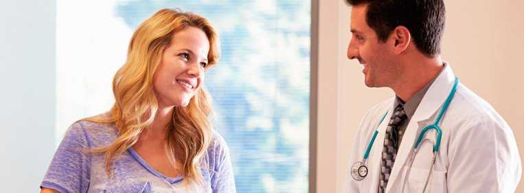 Previna a embolia pulmonar Médico e paciente de pé, sorrindo enquanto conversam