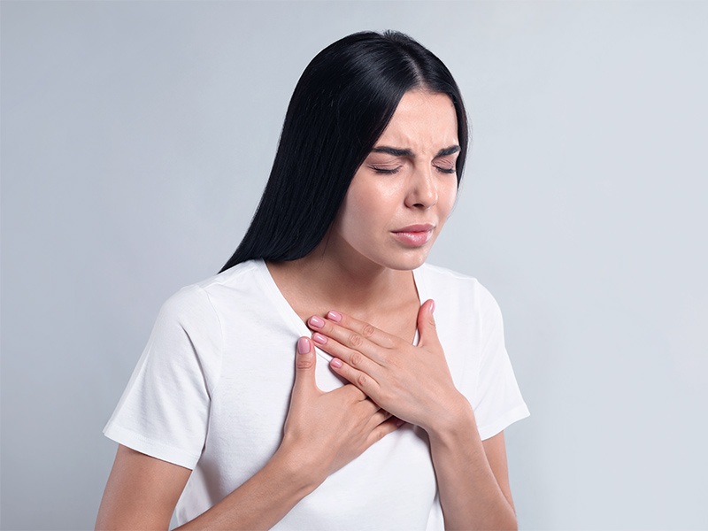 Mulher de camiseta branca com falta de ar, mostrando como a embolia pulmonar é grave