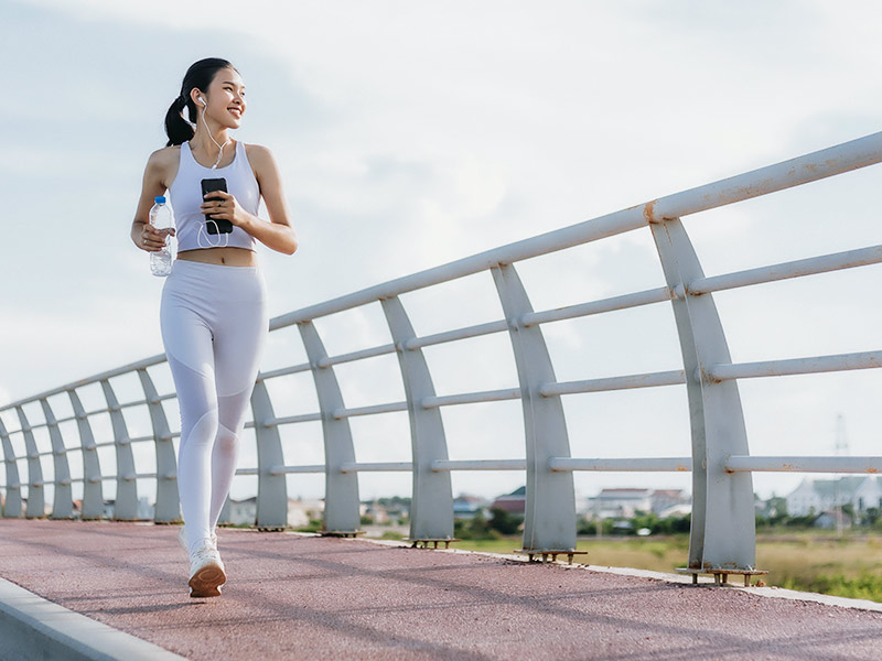 É possível se curar da trombose? Mulher de cropped e legging branca correndo em uma ponte, em busca da cura da trombose