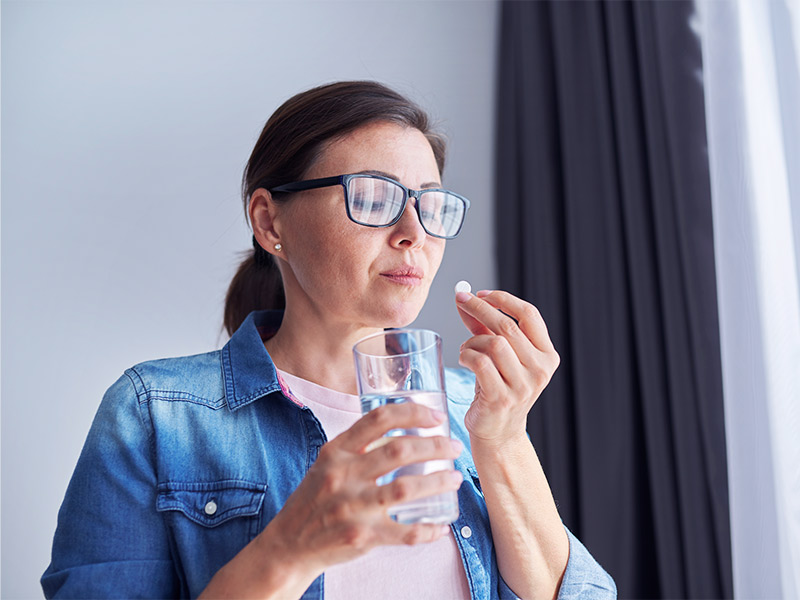 Mulher tomando um comprimido durante o tratamento para trombose venosa profunda