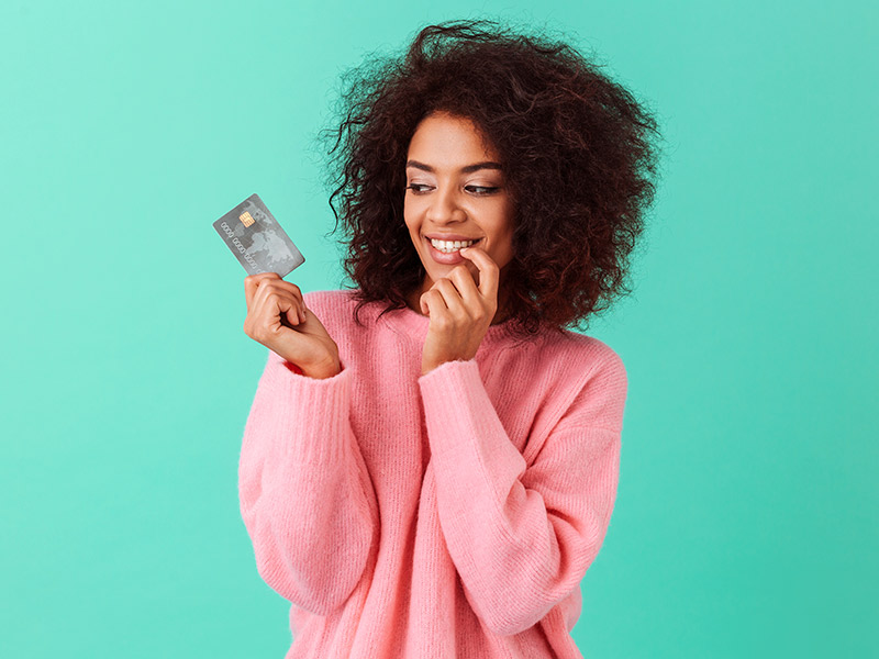 Imagem com fundo azul claro e uma mulher no centro, segurando um cartão de crédito e se questionando quanto custa uma lipo