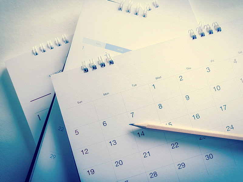Imagem de vários calendários e um lápis por cima deles para ilustrar o tema "a época do ano influencia no valor da lipoaspiração"?