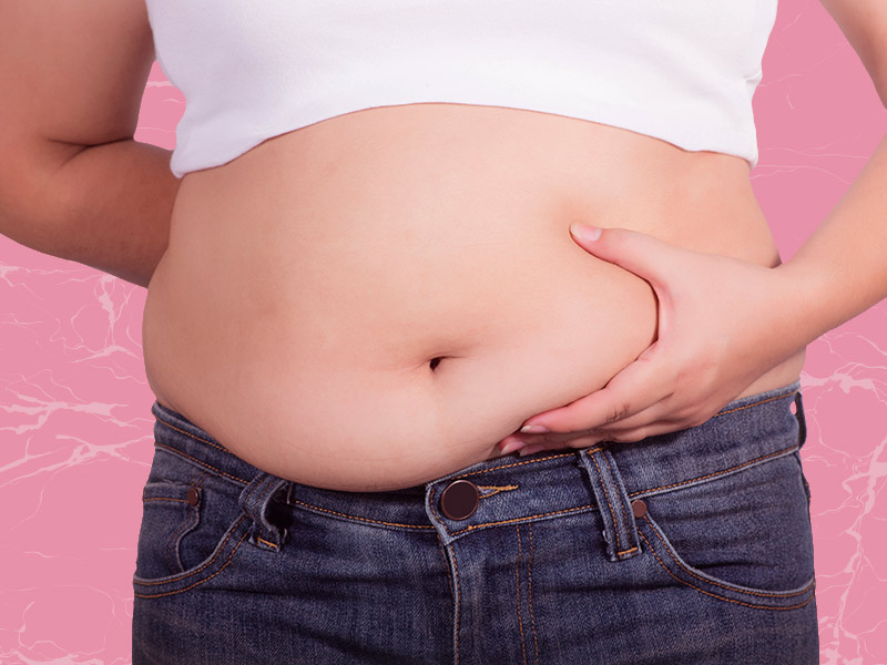 mulher segurando a barriga avantajada pensando nas fotos de antes e depois da lipo light 