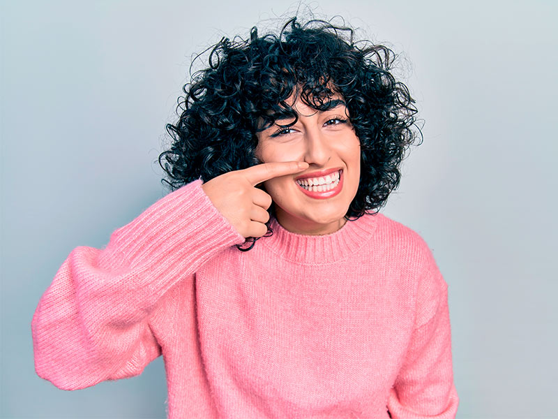 Imagem de uma mulher sorridente ao saber a diferença de preço da rinoplastia e septoplastia