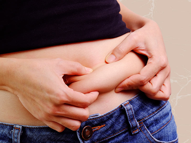 Mulher apertando a barriga, pois quer fazer bambuterapia para gordura localizada