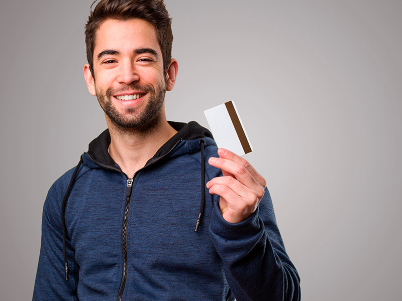 Imagem de um homem segurando um cartão de crédito e expressando felicidade após saber o preço da cirurgia no nariz