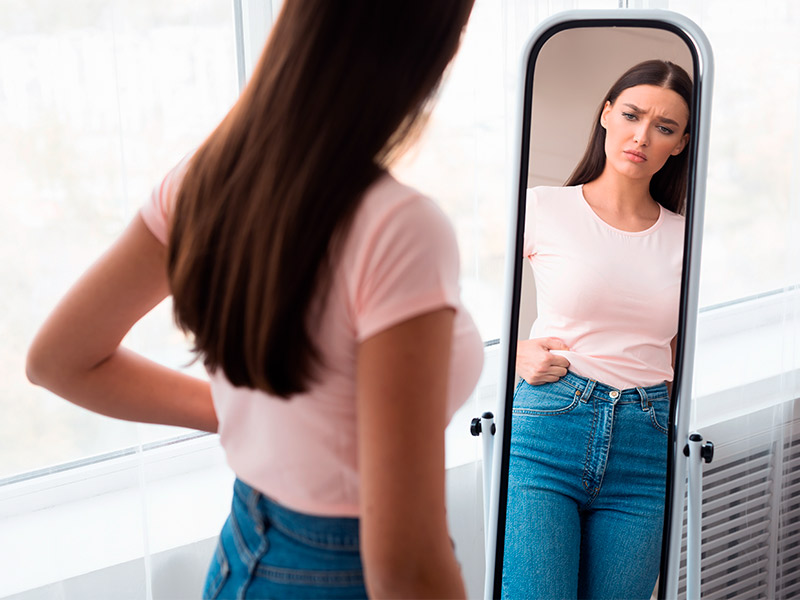Mulher com transtorno dismórfico corporal se olhando no espelho
