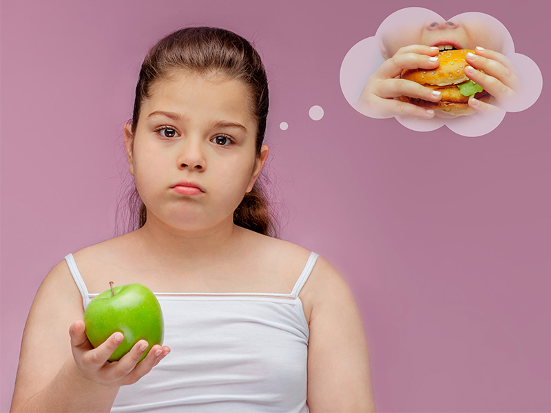 Menina com transtorno de imagem, segurando uma maça e pensando em uma hambúrguer