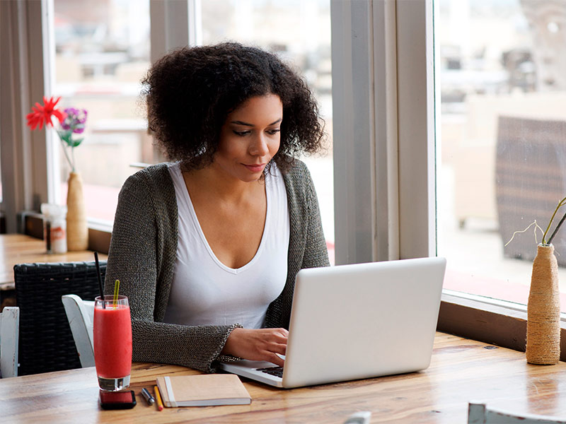 Mulher sentada na mesa, pesquisando no notebook o que é dismorfofobia