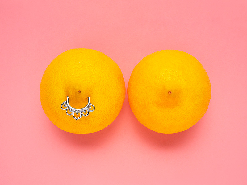 Duas laranjas, uma com um piercing, para mostrar umas das formas de tratar o bico do seio invertido