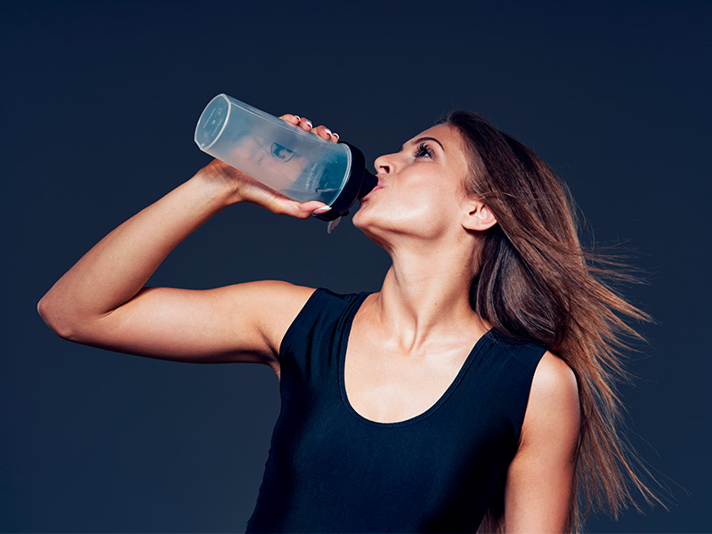 Imagem de uma mulher tomando ácido hialurônico em uma garrafa plástica