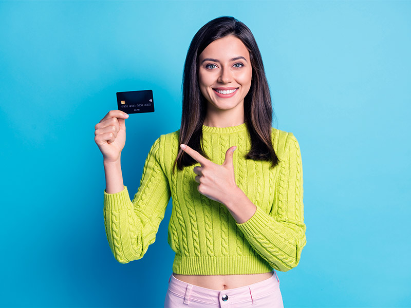 Mulher sorrindo e apontando para um cartão de crédito pensando no preço da bioplastia
