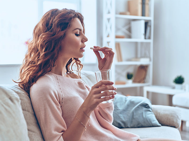 mulher tomando pílula que promete deixar os seios mais bonitos