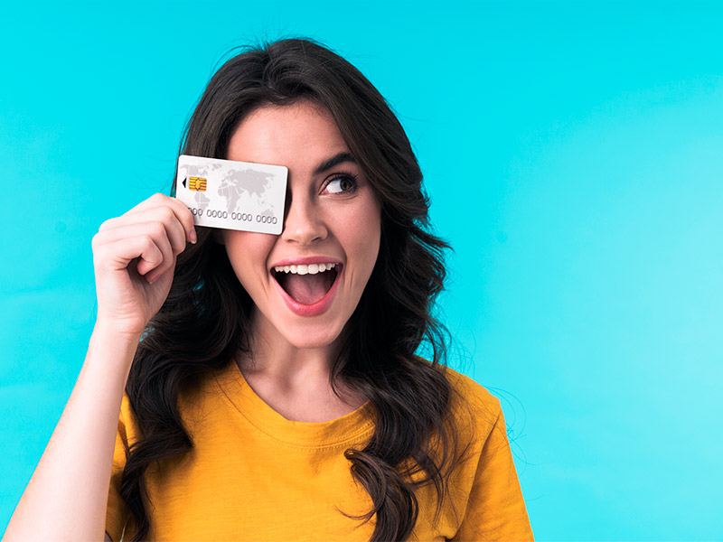 mulher feliz com o preço da cirurgia de lipoma segurando um cartão de crédito na frente do olho