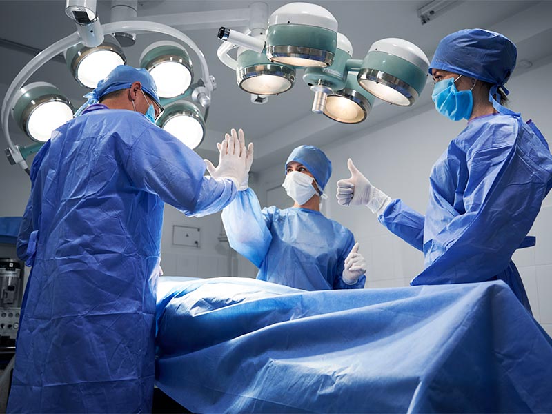 3 médicos no centro cirúrgico dando um ok para começar a cirurgia para afinar o braço