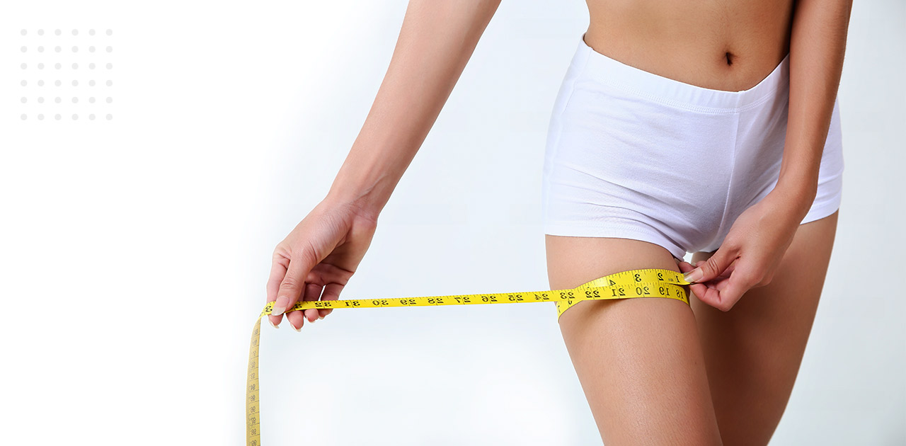 Mulher de shorts branco medindo a coxa direita com fita métrica, pensando na diferença de lifting e lipo nas coxas