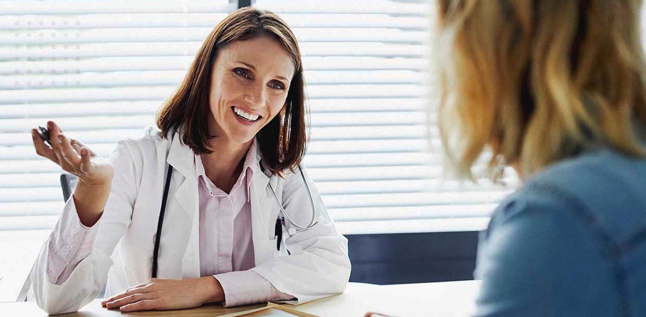 Paciente fazendo perguntas antes do lifting de coxa para médica sorrindo