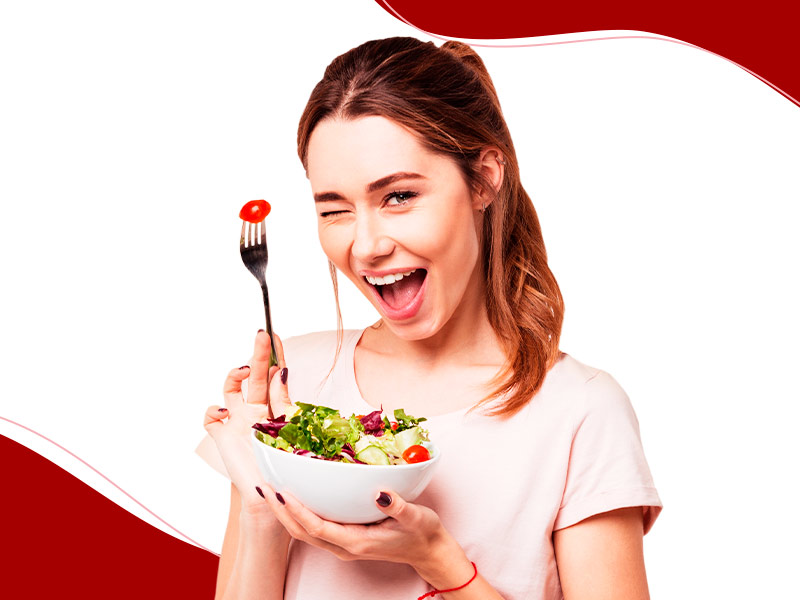 mulher fazendo dieta para chapar barriga, na imagem ela está feliz comendo salada