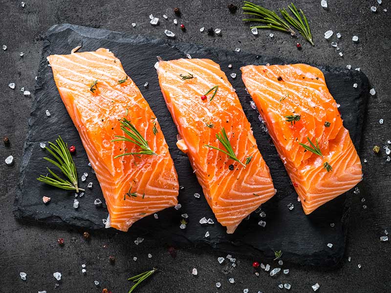 três peças de salmão para chapa barriga em um fundo preto