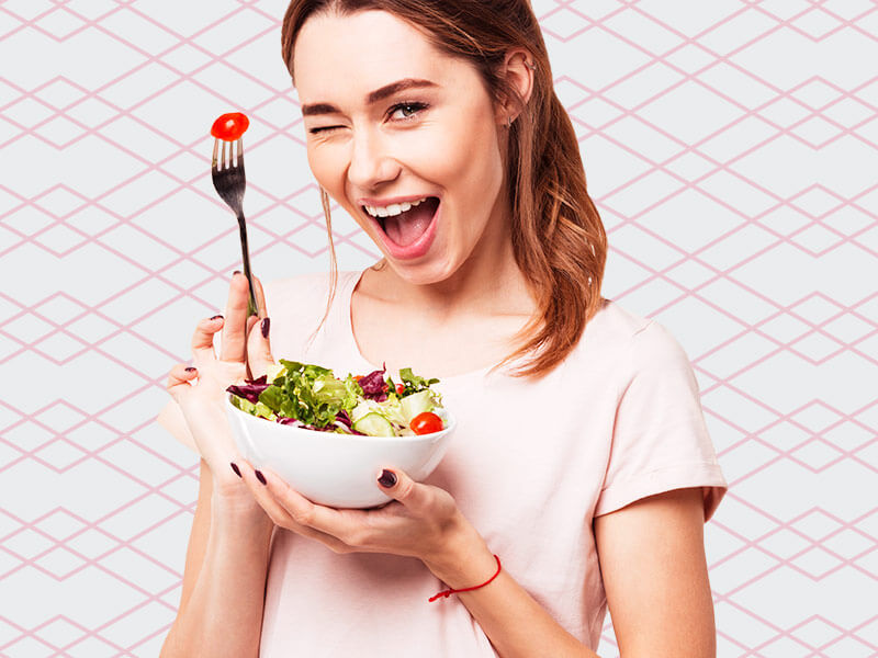 mulher fazendo dieta para chapar barriga, na imagem ela está feliz comendo salada