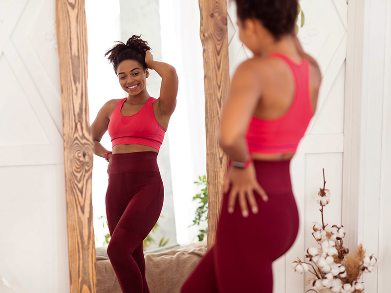 mulher feliz se olhando no espelho depois de como tratar estomago alto