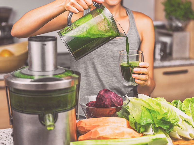 mulher com roupa de academia colocando um suco verde no copo como forma de eliminar gordura nos braços 