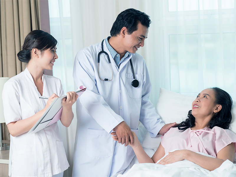 Como é feita a Mamoplastia? Médico e enfermeira explicando para paciente deitada na maca como é feita a Mamoplastia