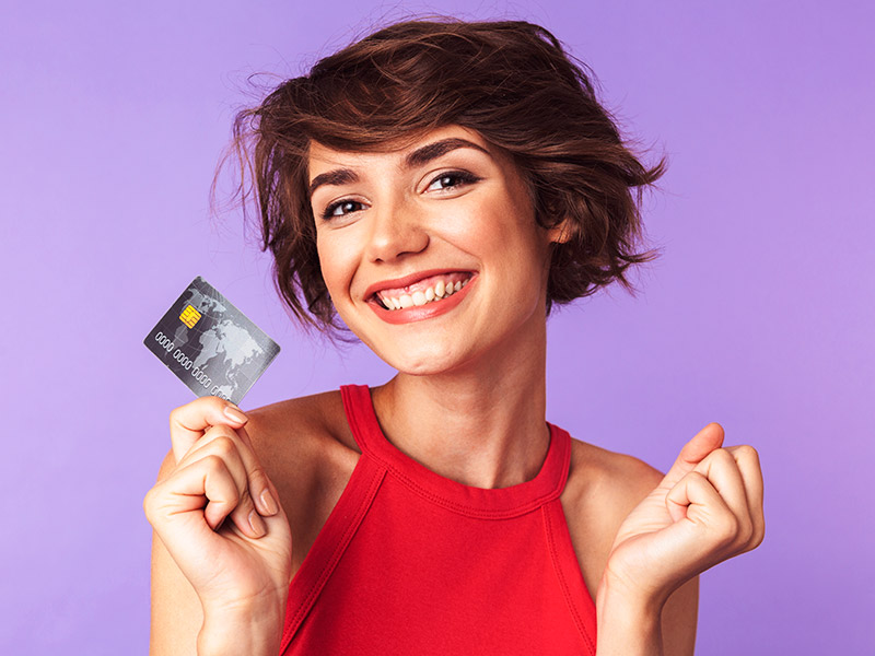Mulher sorrindo segurando um cartão de crédito para pagar o valor da mastopexia sem prótese