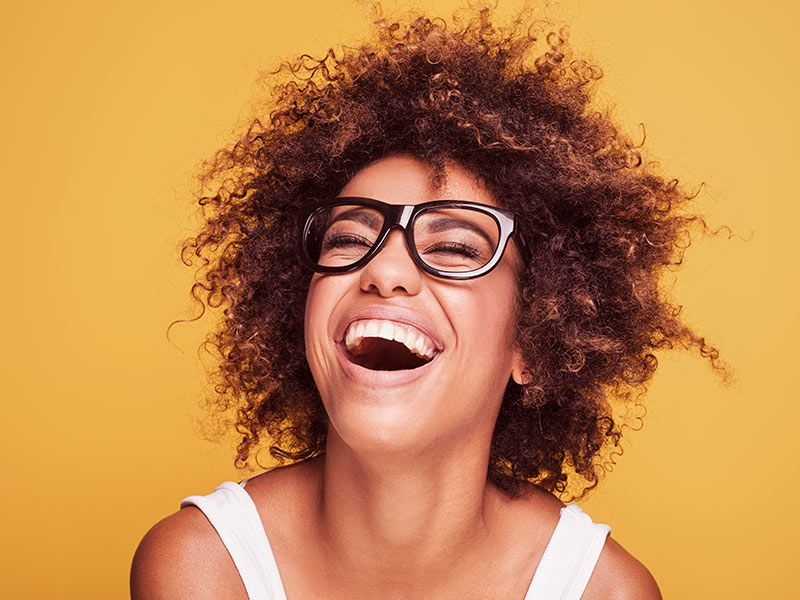 Sua cicatriz ficou feia? Veja as opções de tratamento das cicatrizes da mastopexia Mulher de óculos de grau preto sorrindo depois de descobrir como clarear cicatriz da mastopexia