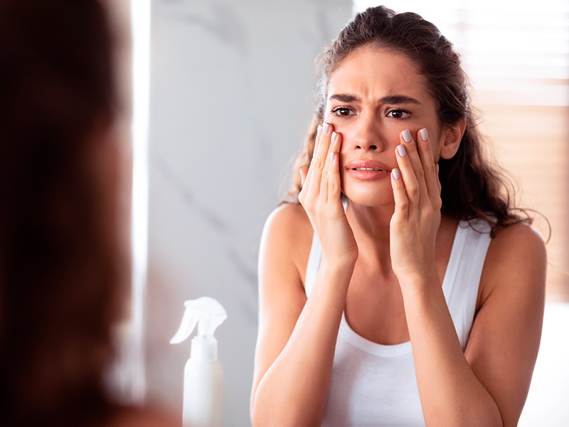 Mulher se olhando no espelho com expressão de medo devido aos riscos da alectomia