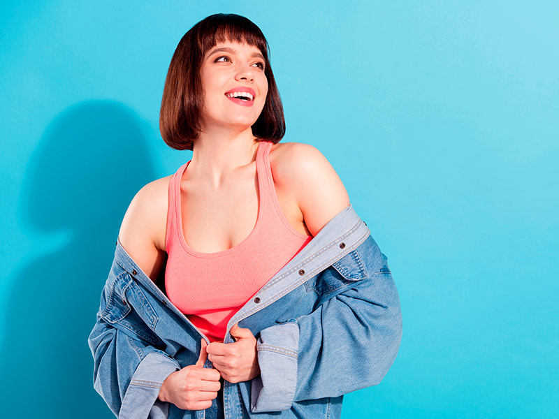Dê o primeiro passo para conquistar uma cicatriz de mamoplastia discreta Mulher sorrindo olhando para cima feliz