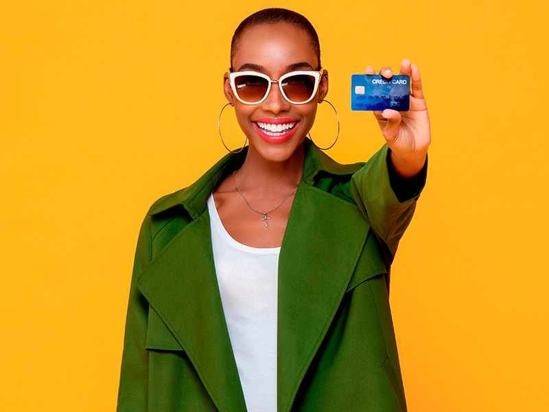 Imagem de uma mulher segurando um cartão de crédito e expressando felicidade após saber a média de preço da rinoplastia secundária 