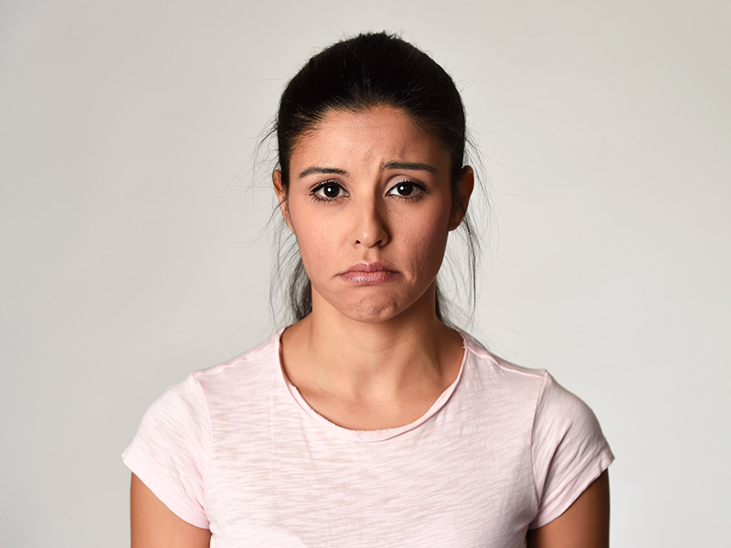 Foto de uma mulher visivelmente triste por causa da técnica de otoplastia fechada
