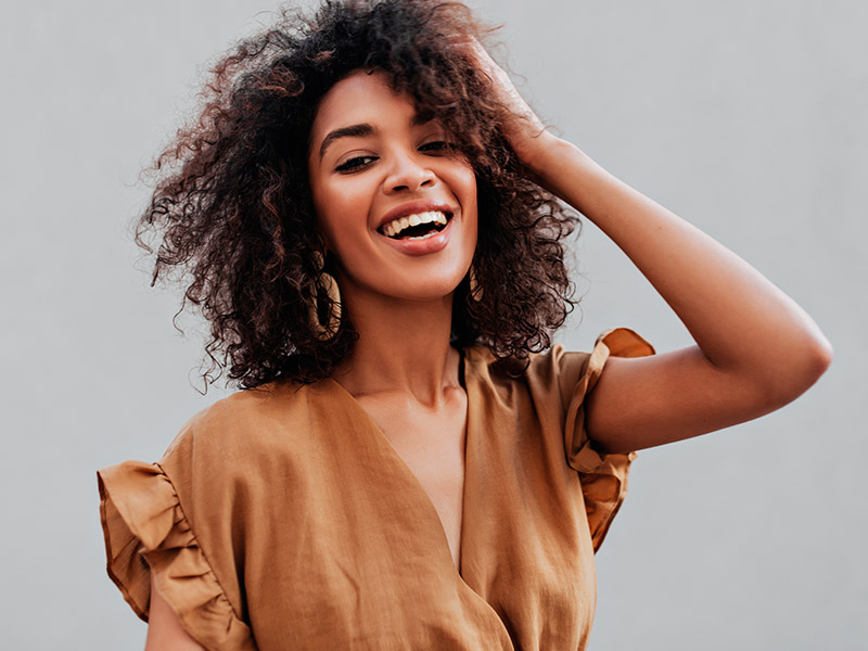 Mulher sorrindo com a mão na cabeça, depois de descobrir o seu tipo de mamilo