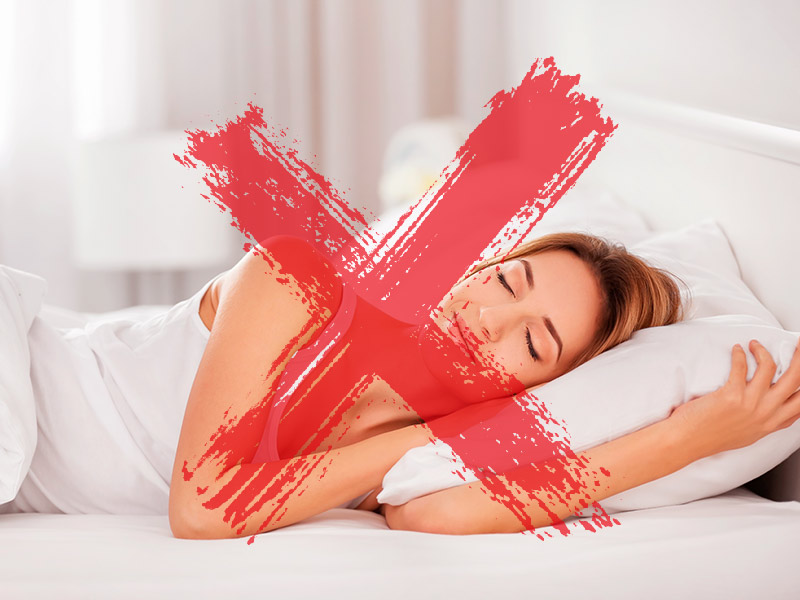 Mulher dormindo de lado e um X vermelho em cima demonstrando que não pode dormir dessa forma no pós-operatório