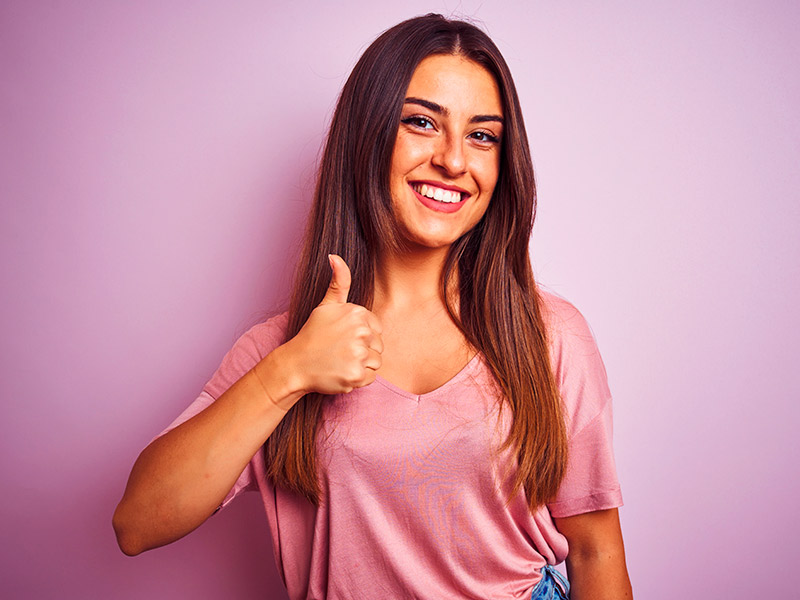 Mulher sorrindo fazendo um jóia no seu pós-operatório da otoplastia 