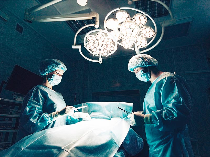 Dois cirurgiões realizando uma cirurgia plástica dentro de um hospital