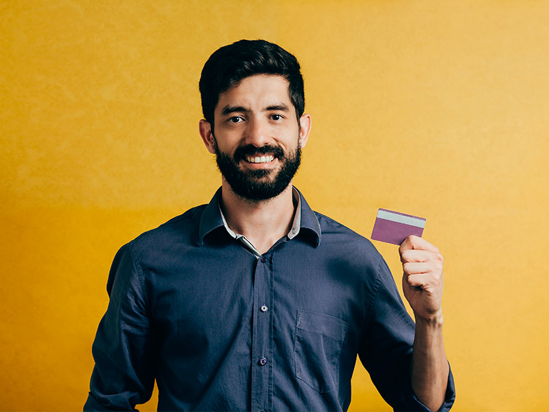 Homem segurando um cartão de crédito para pagar o preço da cirurgia de ginecomastia 