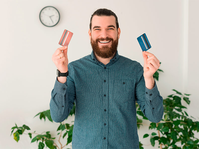 Homem sorrindo segurando dois cartões como forma de pagamento da operação de ginecomastia 