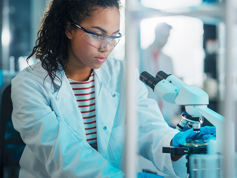 Imagem de uma pesquisadora observando os tipos de toxina botulínica em um microscópio