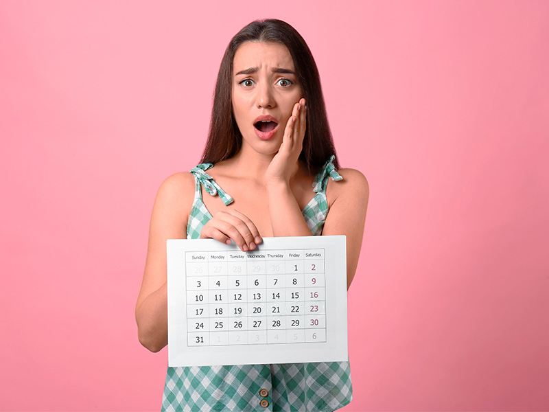 Imagem de uma mulher com expressão de decepção por causa do procedimento que deu errado, segurando um calendário 