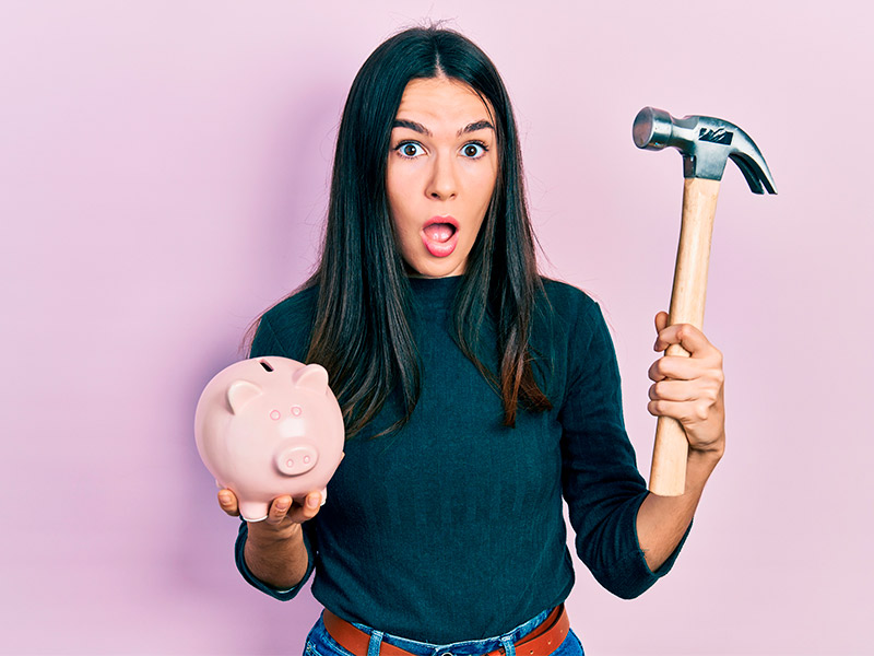 Imagem com fundo rosa e uma mulher com expressão de surpresa ao saber o preço do lifting facial. A modelo segura um cofrinho em formato de porco e um martelo. 