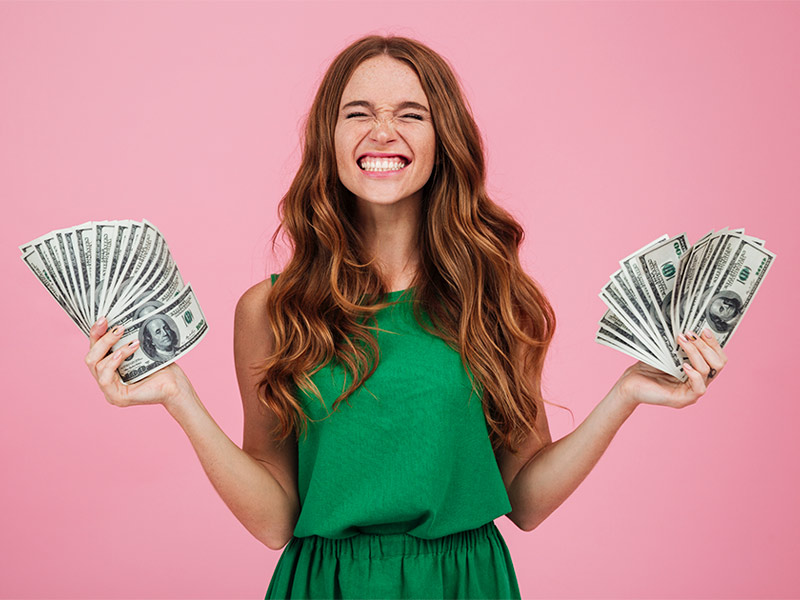 Imagem de uma mulher segurando notas de dinheiro e sorrindo ao saber a média de preça da torsoplastia 